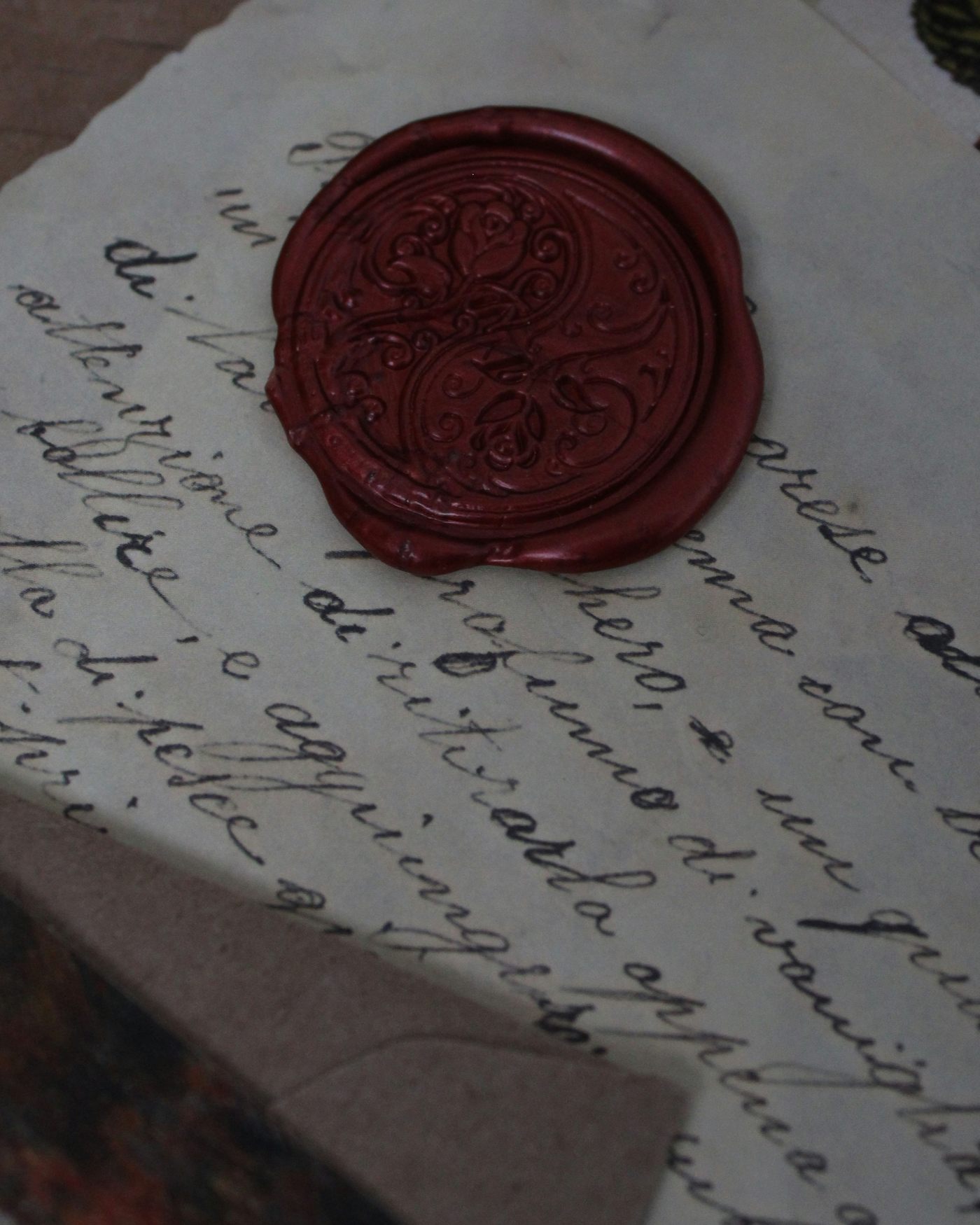 A red wax seal stamped with a rose design on a handwritten letter